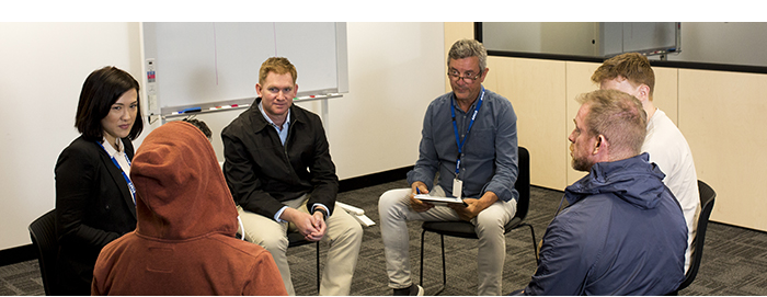 Two clinicians and three service users sitting in a circle in a session.