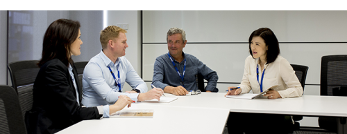 A group of four clinicians sitting and talking at a corner table